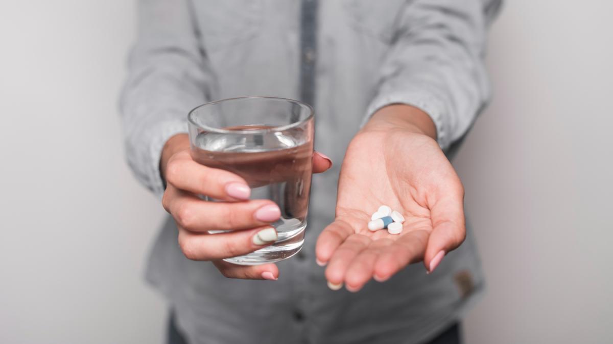 Человек принимает таблетку, запивая водой (рука, таблетка)