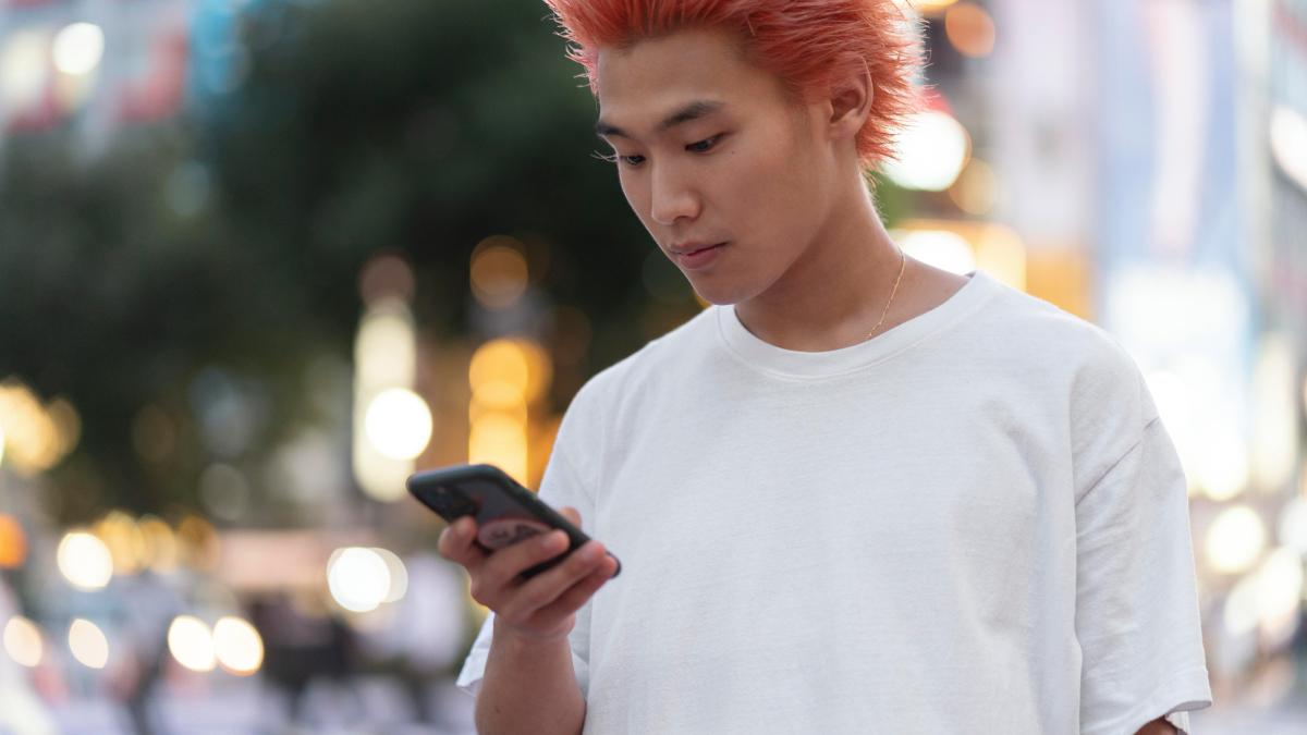 Китаец с рыжими волосами со смартфоном