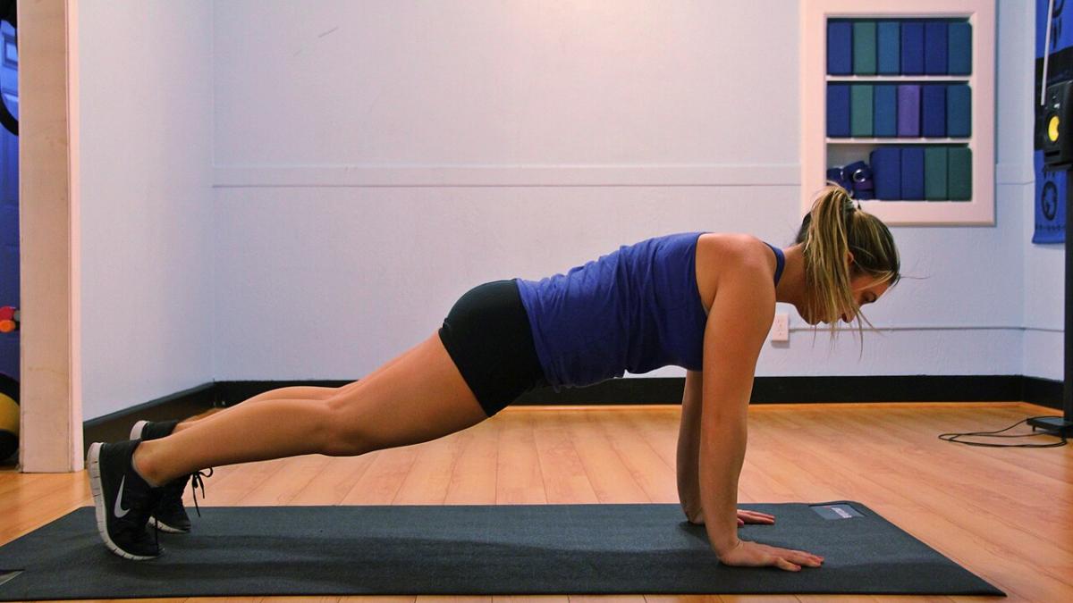 Девушка стоит в планке на прямых руках
