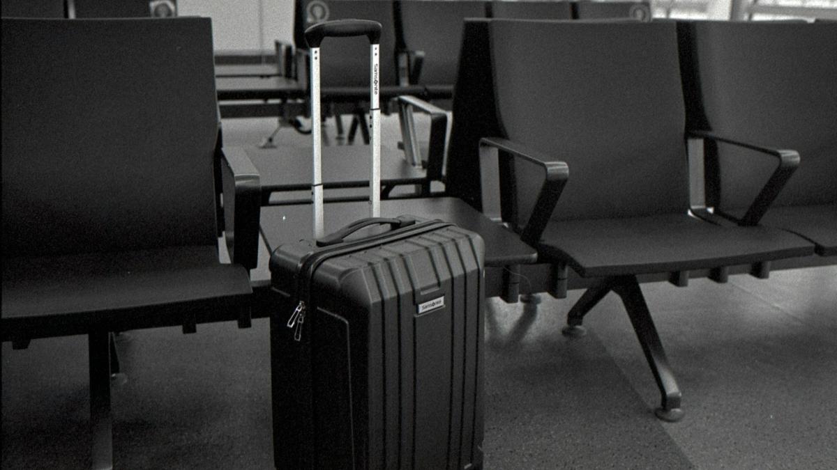 Чемодан на колесиках в зале аэропорта (крупный план)