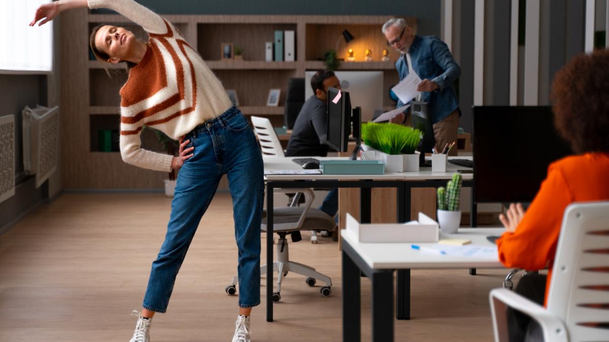 Женщина в офисе растягивается в течение рабочего дня