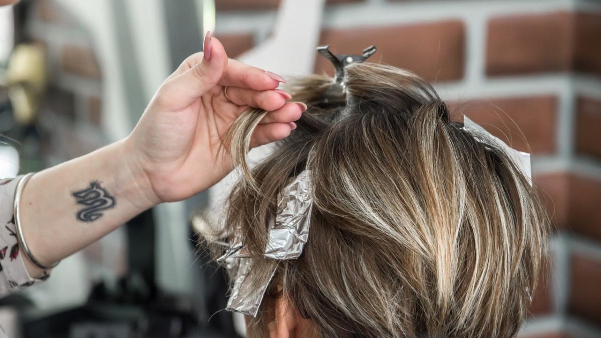 Процесс окрашивания корней волос в салоне (крупный план кисти и фольги)