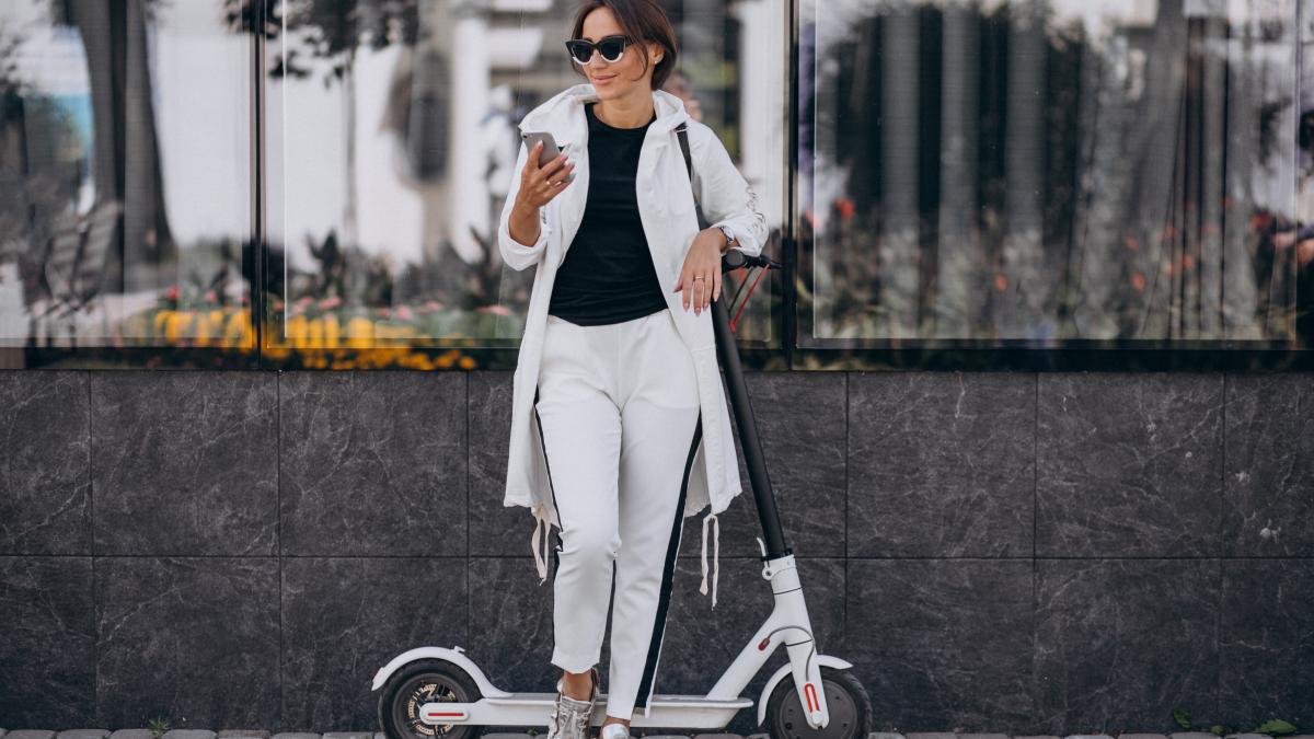 Красивая женщина в белом с самокатом