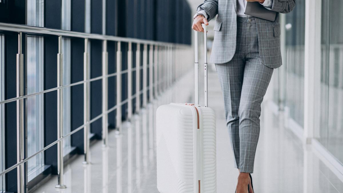 Деловая женщина с чемоданом и ноутбуком в аэропорту