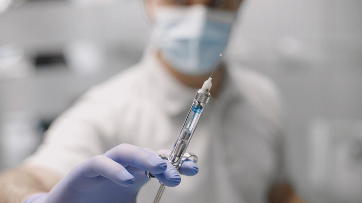 Доктор держит в руке шприц