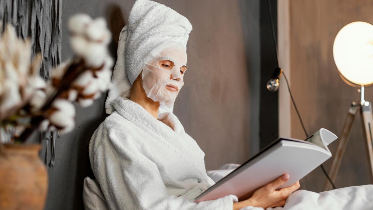 Женщина в халате с маской на лице и журналом