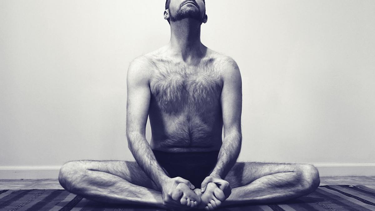 Мужчина сидит в позе бабочки