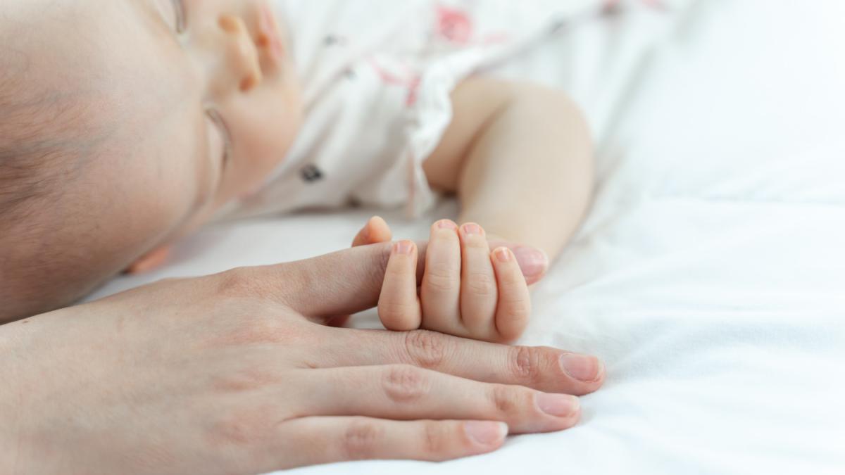 младенец держит руку матери