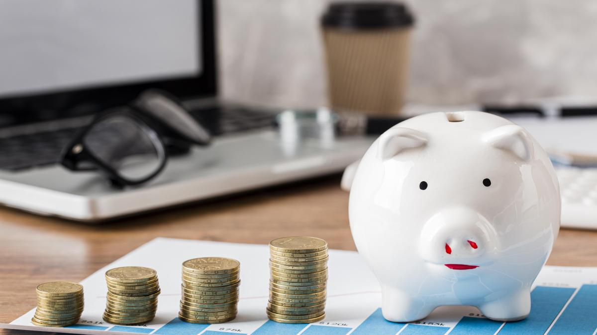 Свинья-копилка и монеты на столе