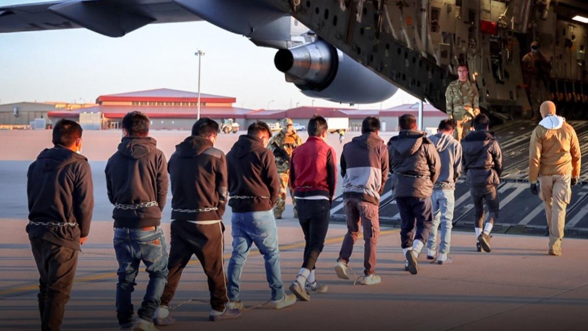 Мигранты в США в наручниках и цепях следуют к военным самолетам Мигранты в США в наручниках и цепях следуют к военным самолетам