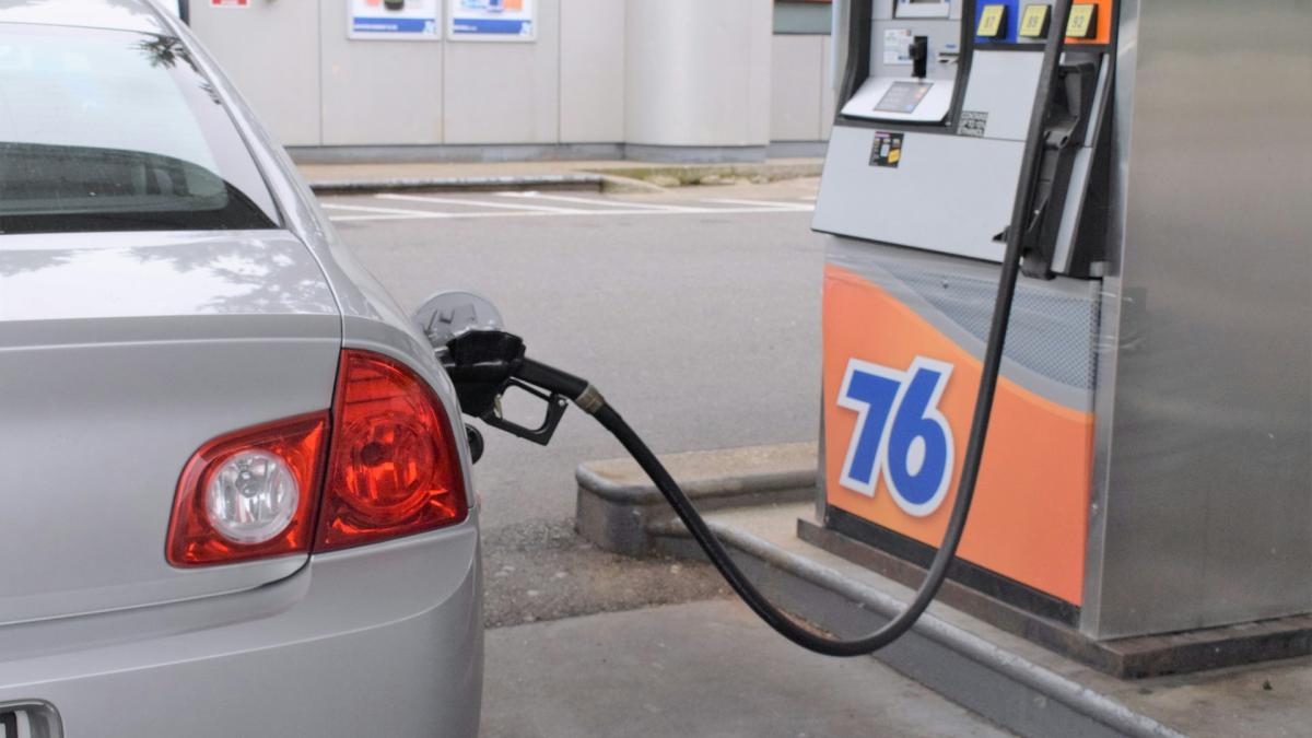 Заправочный пистолет в баке, крупный план счетчика на АЗС с ценой