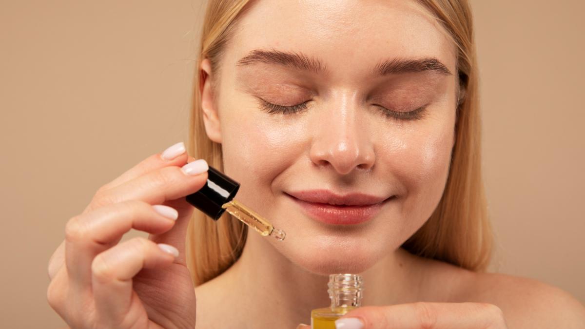 Девушка наносит сыворотку на лицо