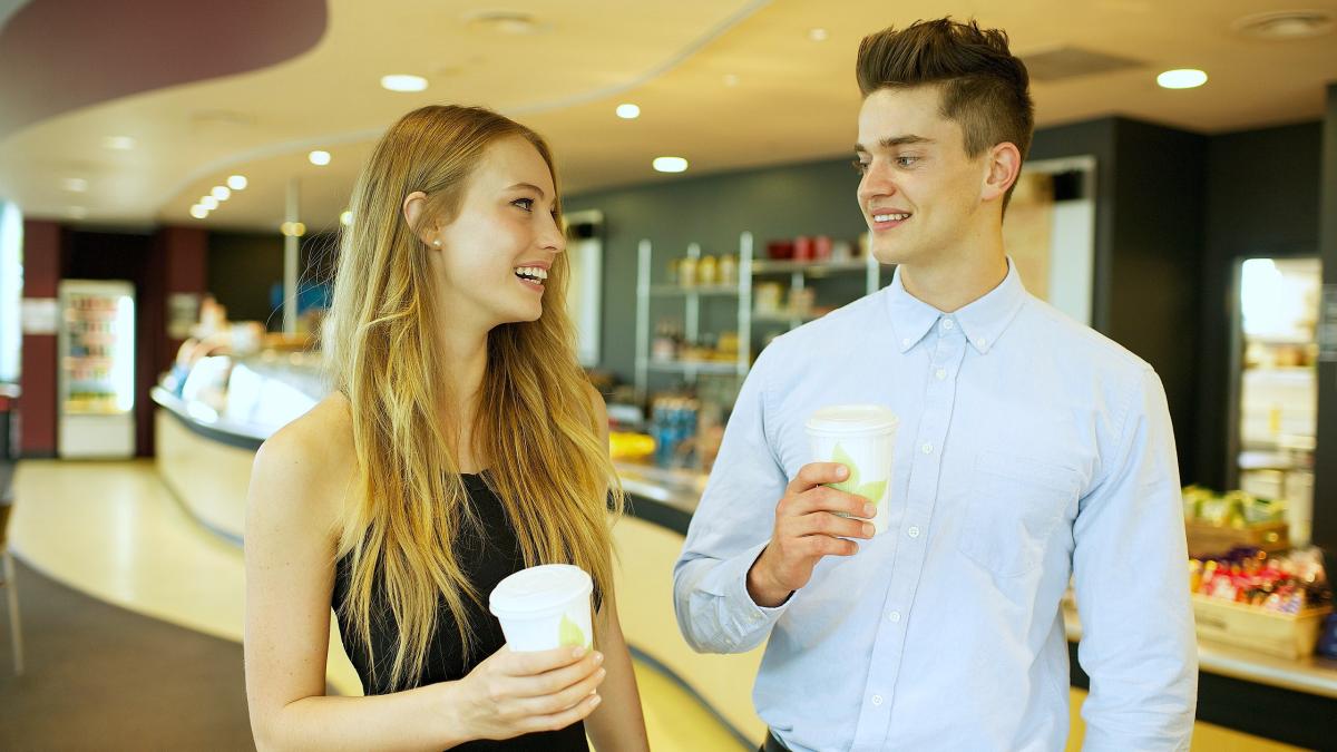 Мужчина и женщина, держащие в руках напиток возле кафе в Центре открытий CSIRO.