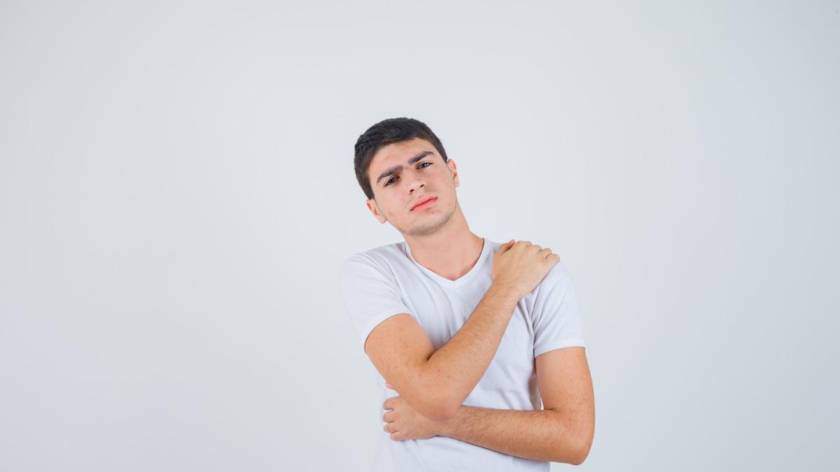 Мужчина держит больное плечо