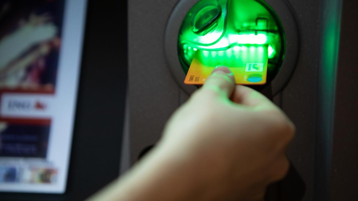 Человек засовывает карту в банкомат